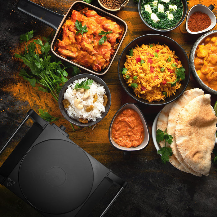 Zoomgoods HP1 BK electric hot plate aesthetically shown in top-down view surrounded by dishes like rice, butter chicken, naan